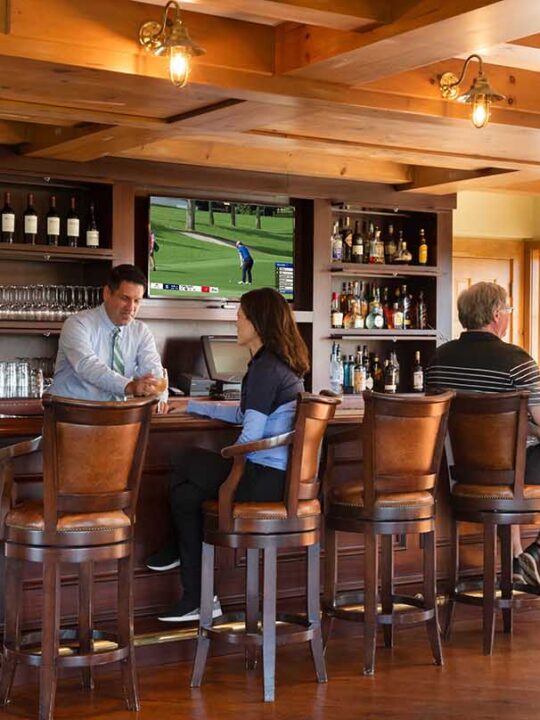 Golf members sitting at the bar at Lake Winnipesaukee Golf Club socializing.