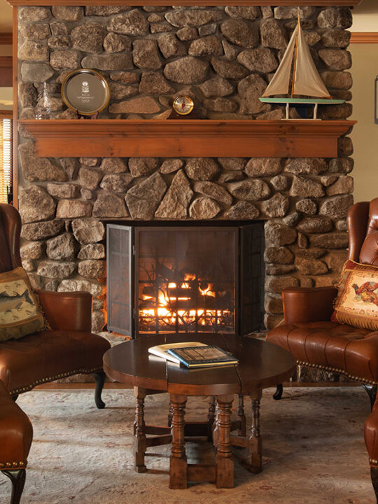 A cozy sitting area with a fireplace lit at Lake Winnipesaukee Golf Club.