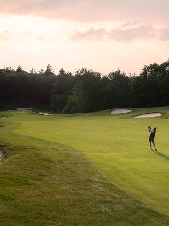 A golfer swinging his club at Lake Winnipesaukee Golf Club on the course.