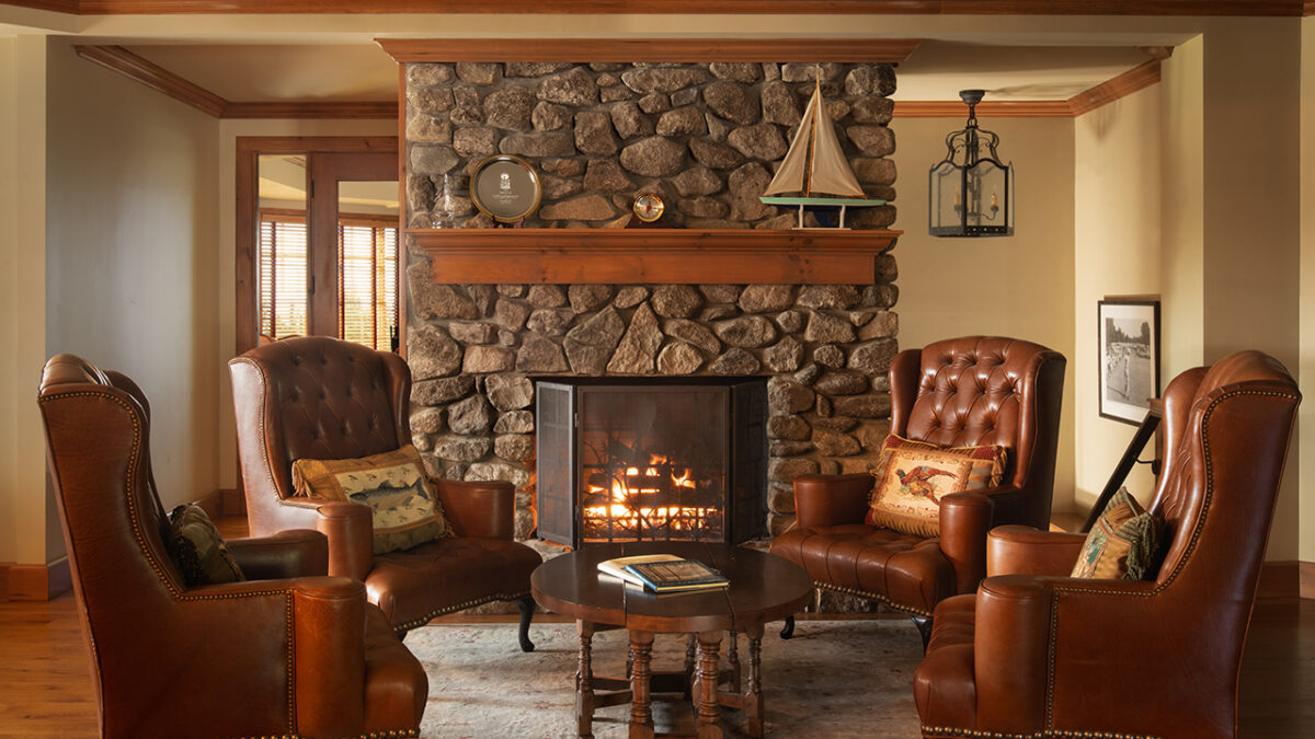 The Club House sitting area with a lit fireplace at Lake Winnipesaukee Golf Club.