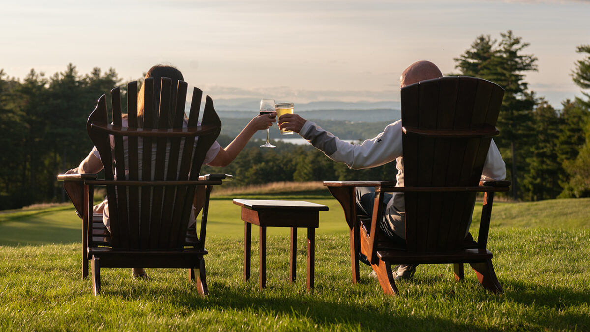 A couple sitting in lawn chairs with a drink in their hand at Lake Winnipesaukee Golf Club.