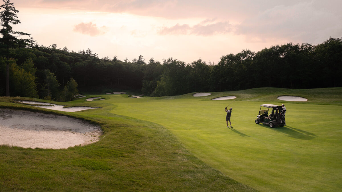 A golfer and golf cart on the golf course at Lake Winnipesaukee Golf Club.