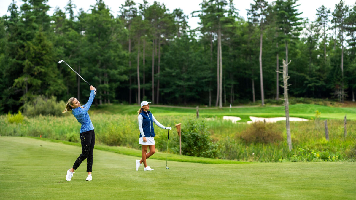 Two women golfers taking an iron shot on a fairway at Lake Winnipesaukee Golf Club.